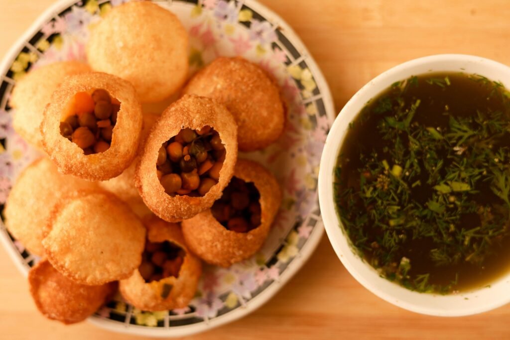 Close-up of crispy panipuri with flavorful filling and spicy water served in a bowl.